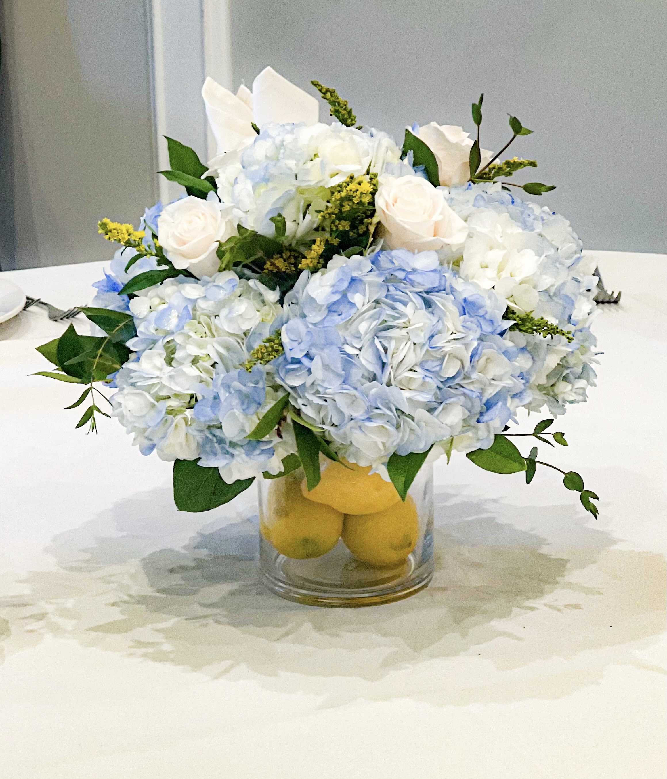 Blue and white flower arrangement in a glass vase with lemons