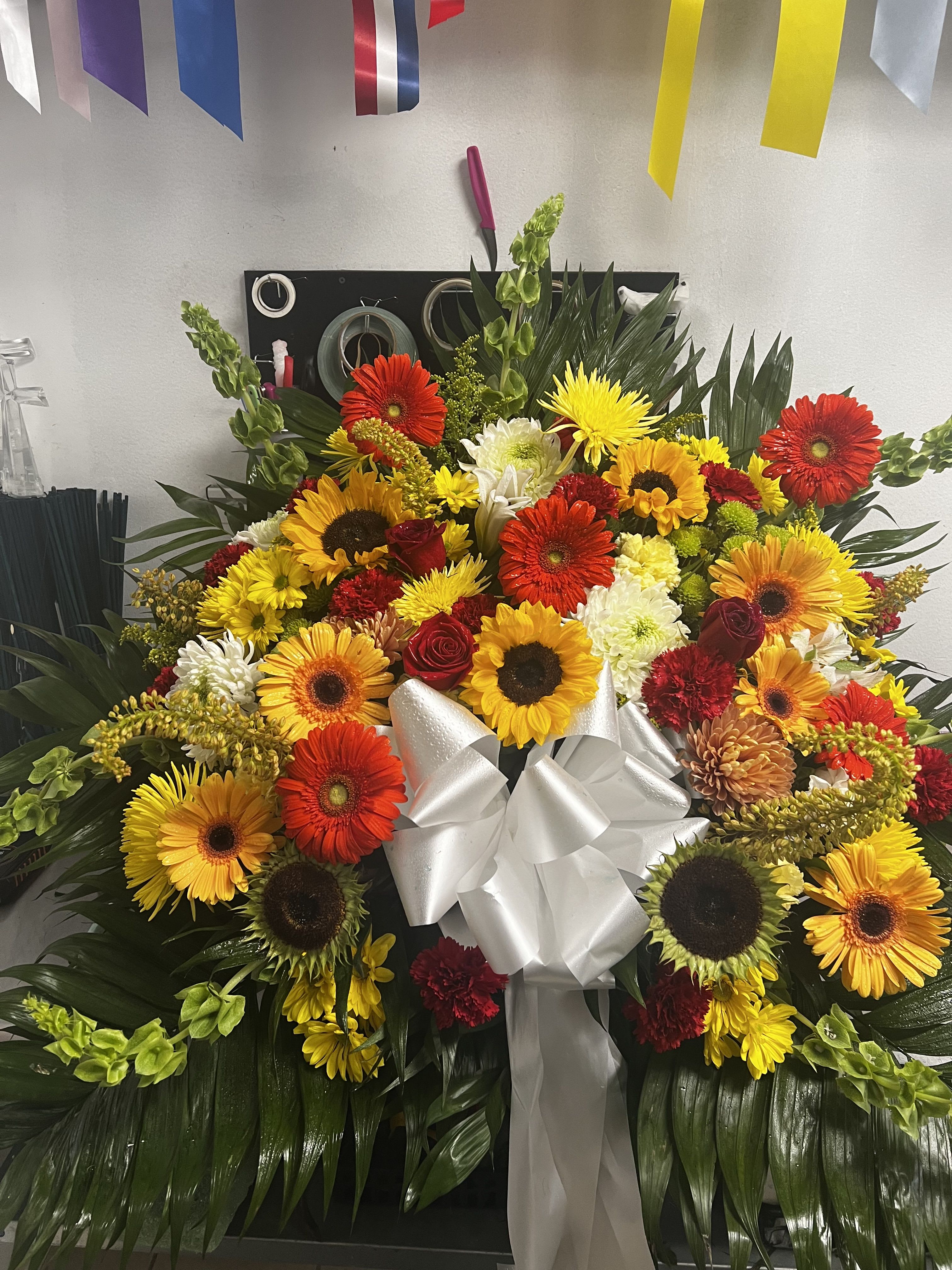 Large mixed flower arrangement with a white ribbon bow