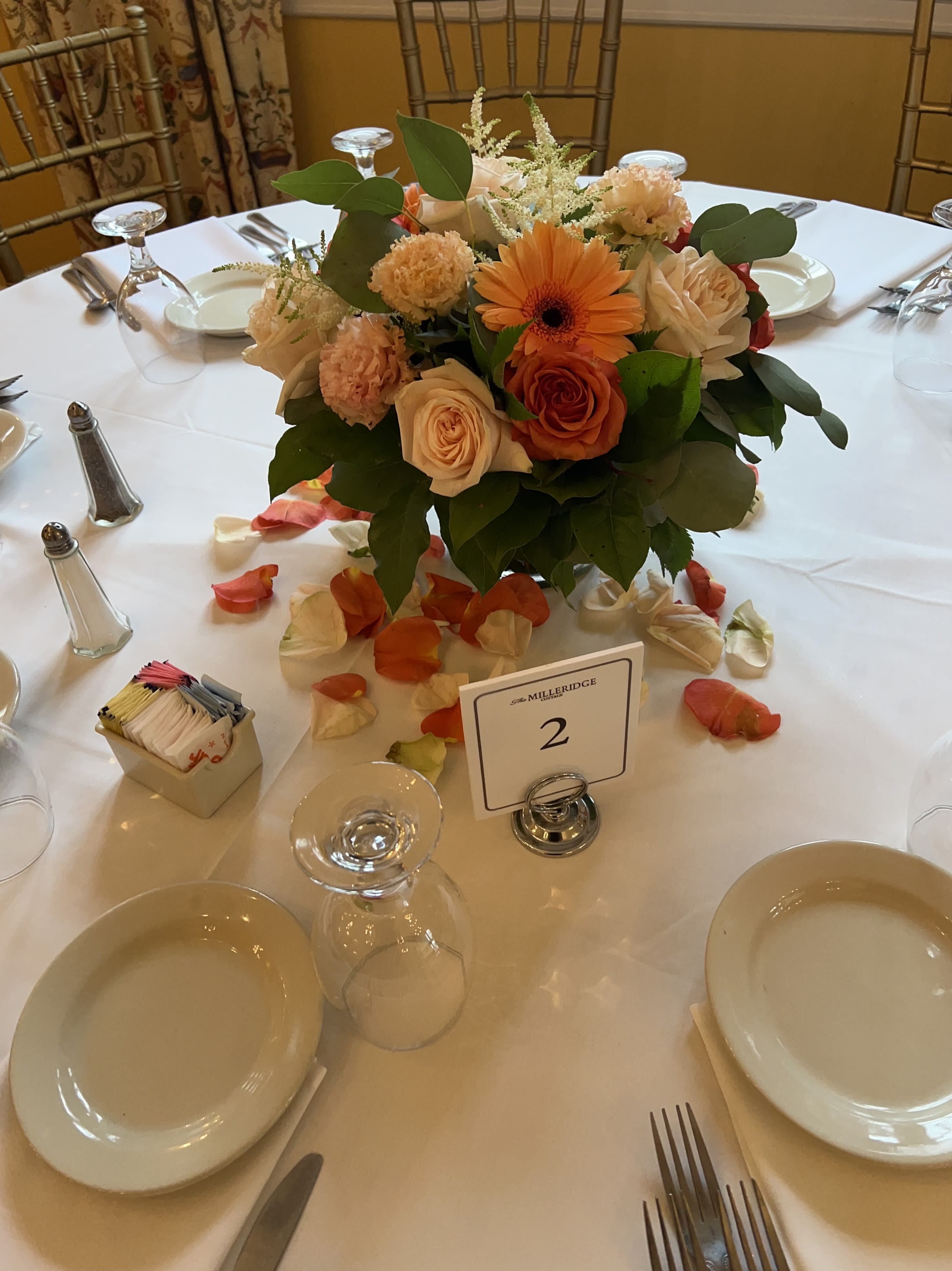 Round table centerpiece with peach and orange flowers in a low arrangement
