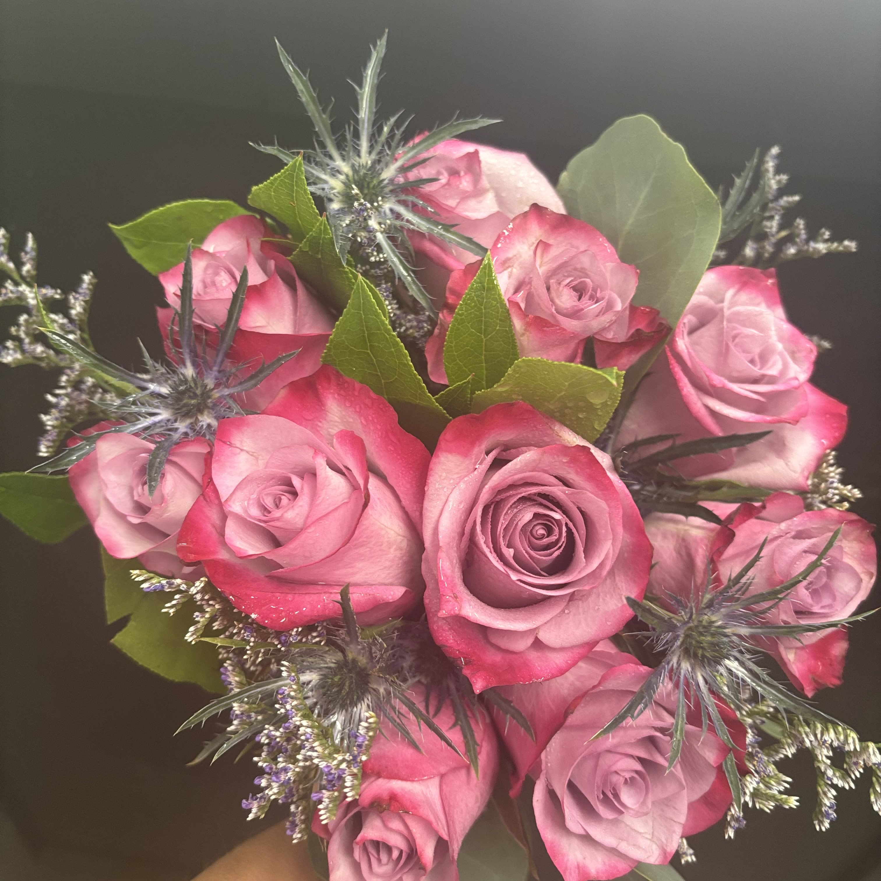 Bouquet of pink roses with spiky blue thistle and greenery