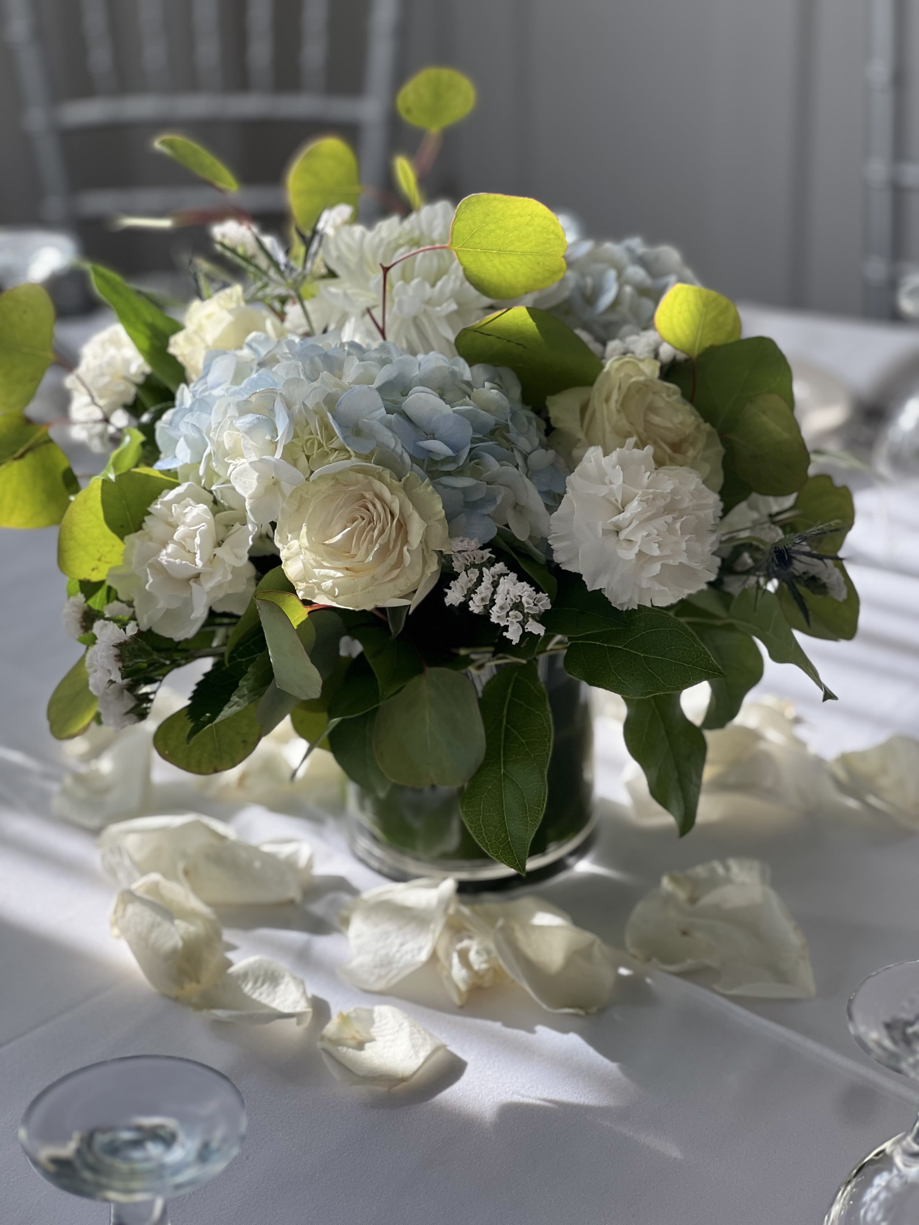 White and pale blue floral centerpiece in a glass vase