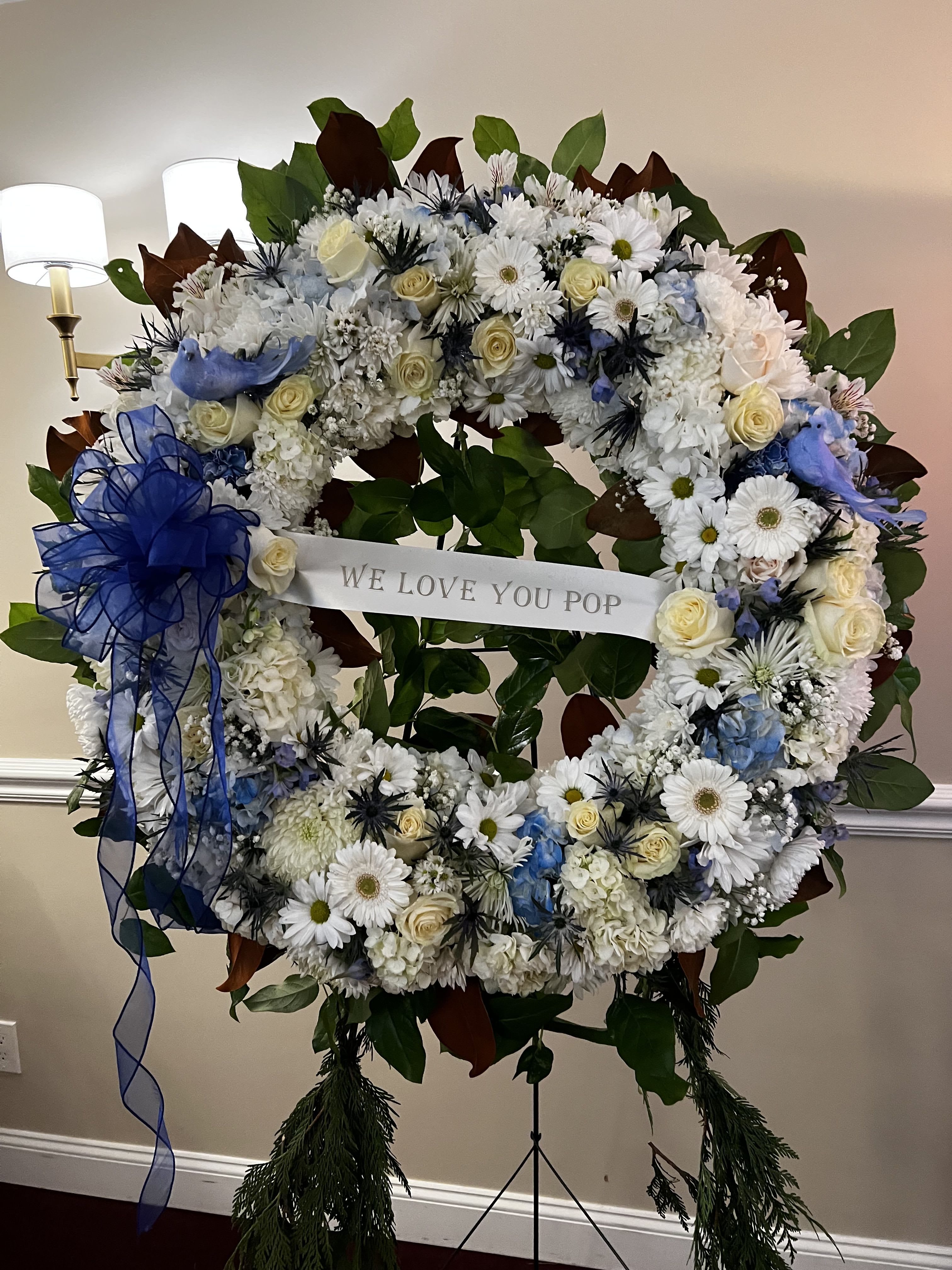 Large floral wreath with white and blue flowers and a ribbon banner