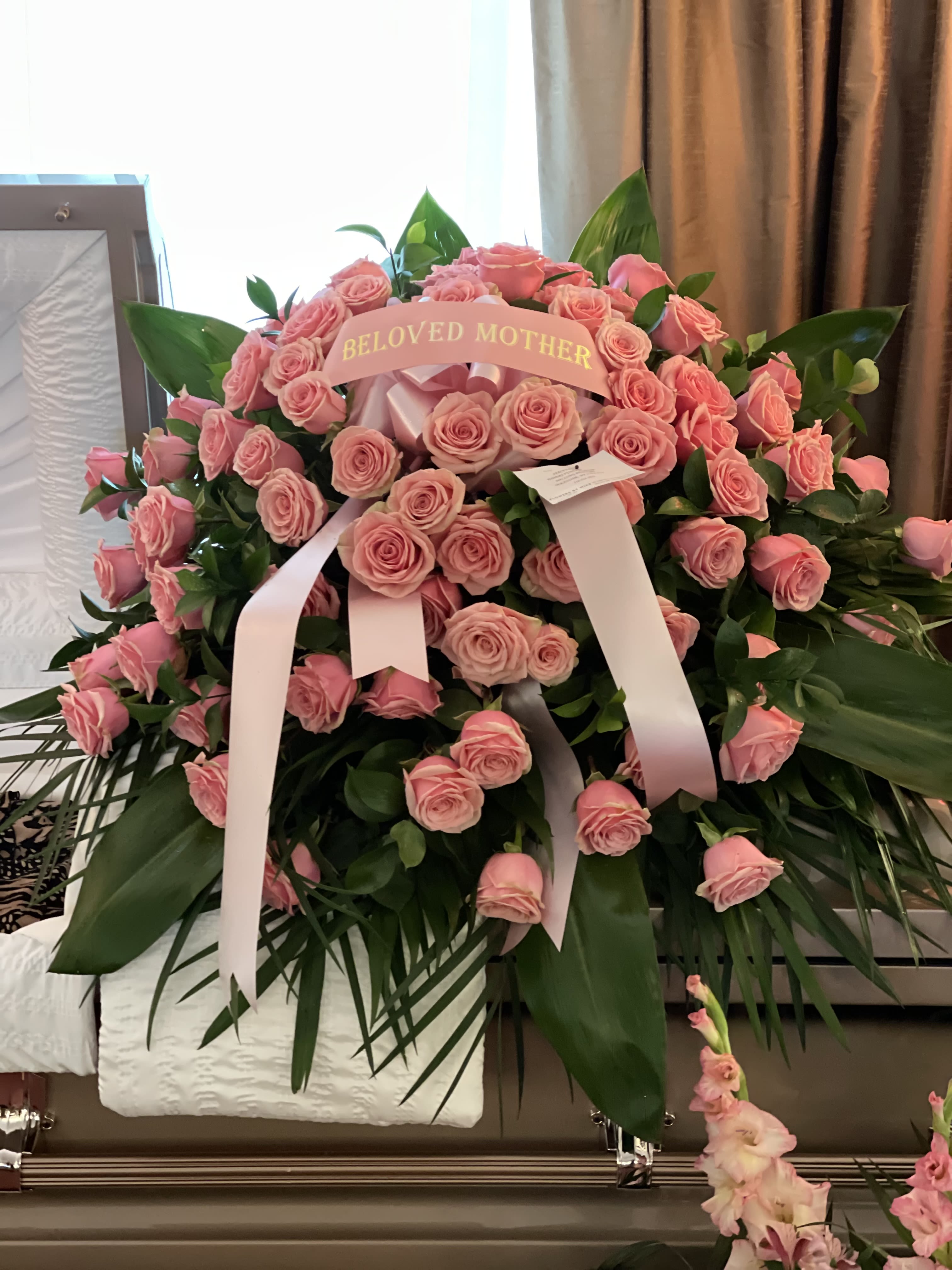 Pink rose funeral spray with a "Beloved Mother" ribbon