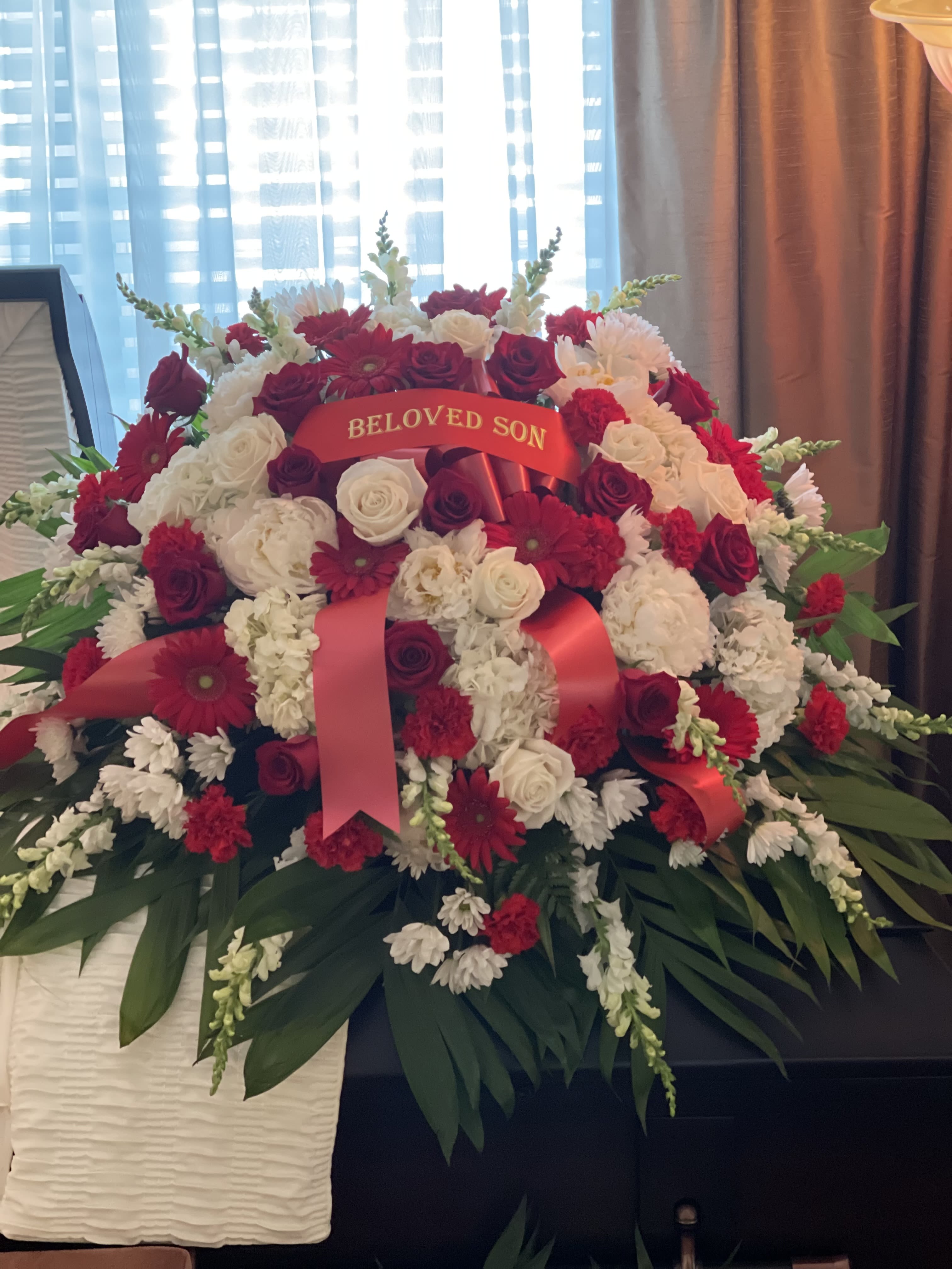 Large red and white funeral spray with a "Beloved Son" ribbon
