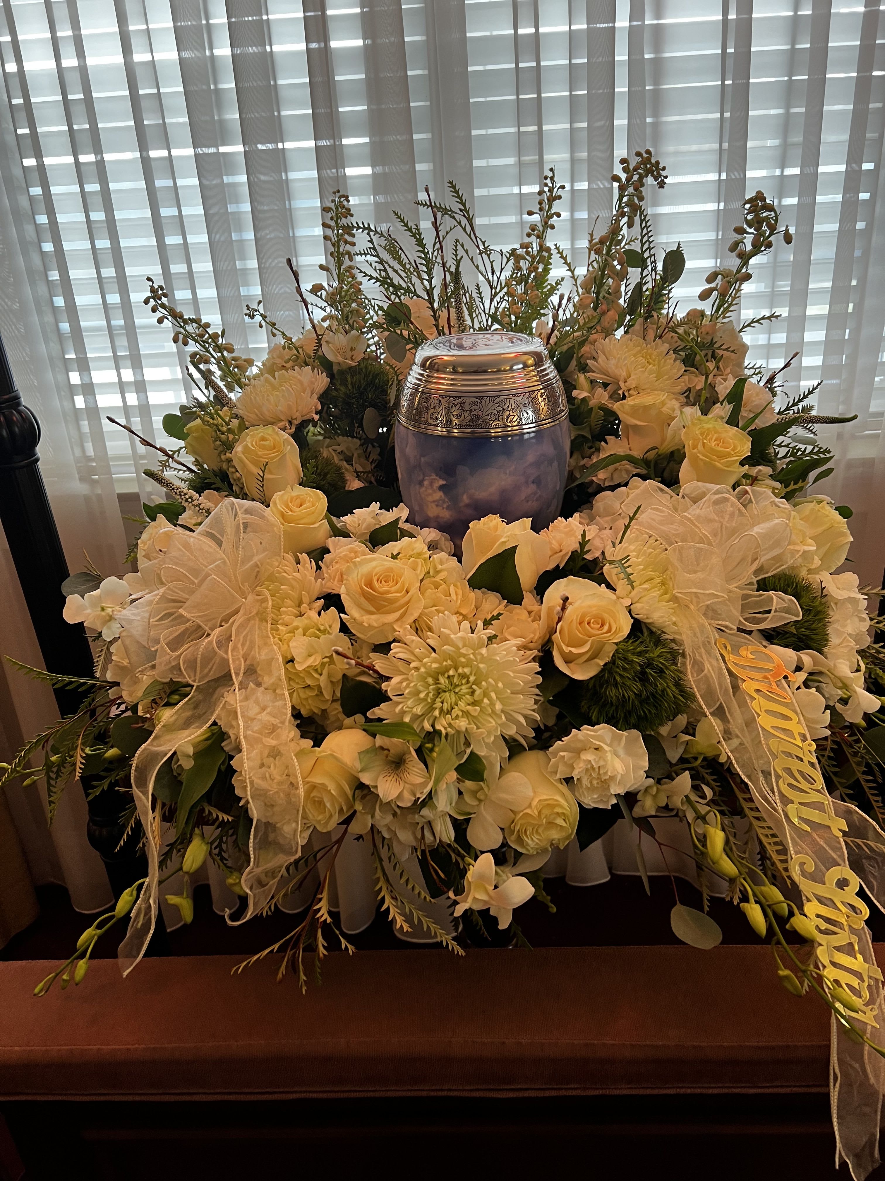 White floral funeral arrangement with a silver urn in the center