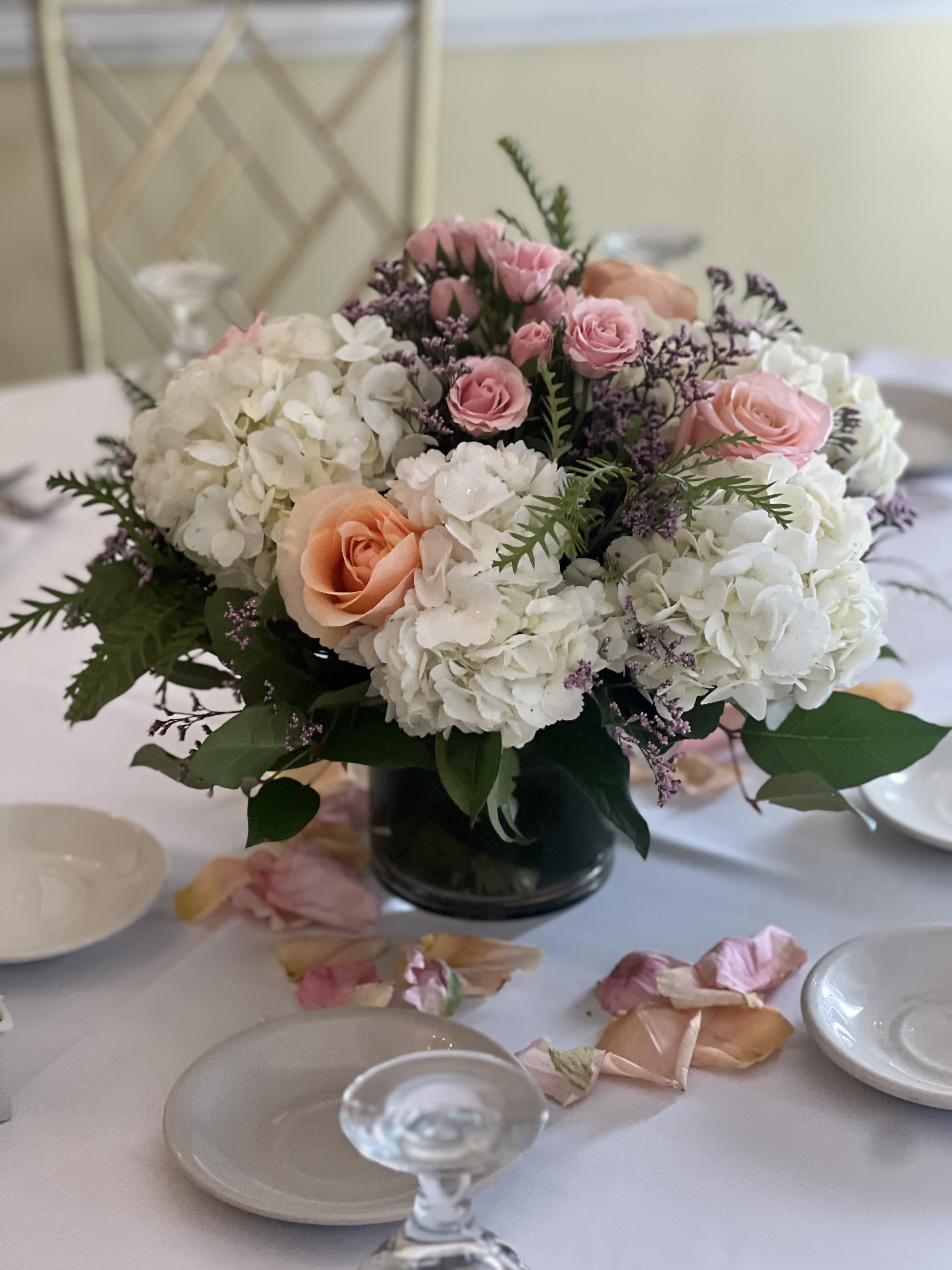 Pink and white floral centerpiece in a dark vase on a set table
