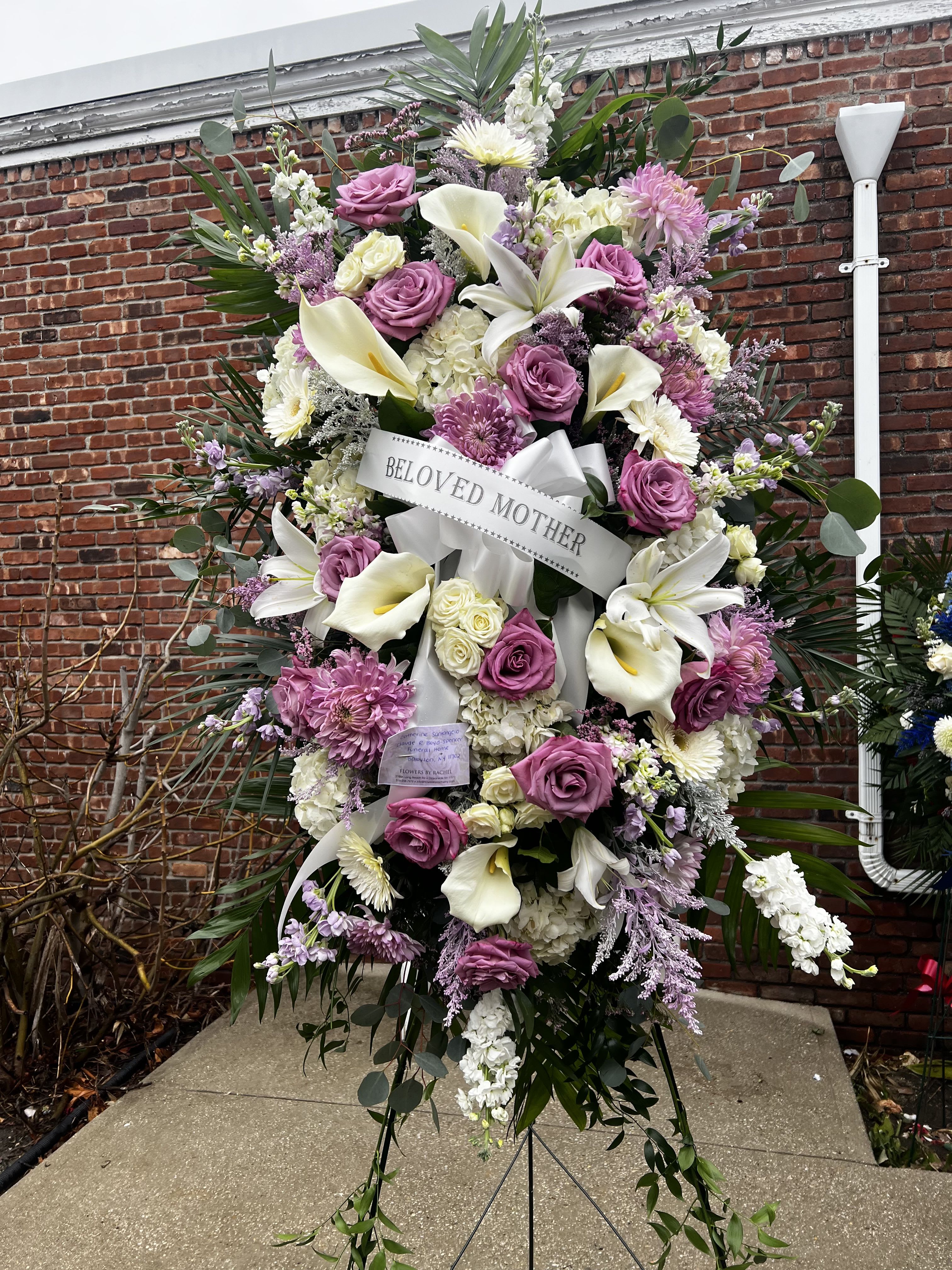Large standing sympathy spray with pink roses, white lilies, and a ribbon reading Beloved Mother