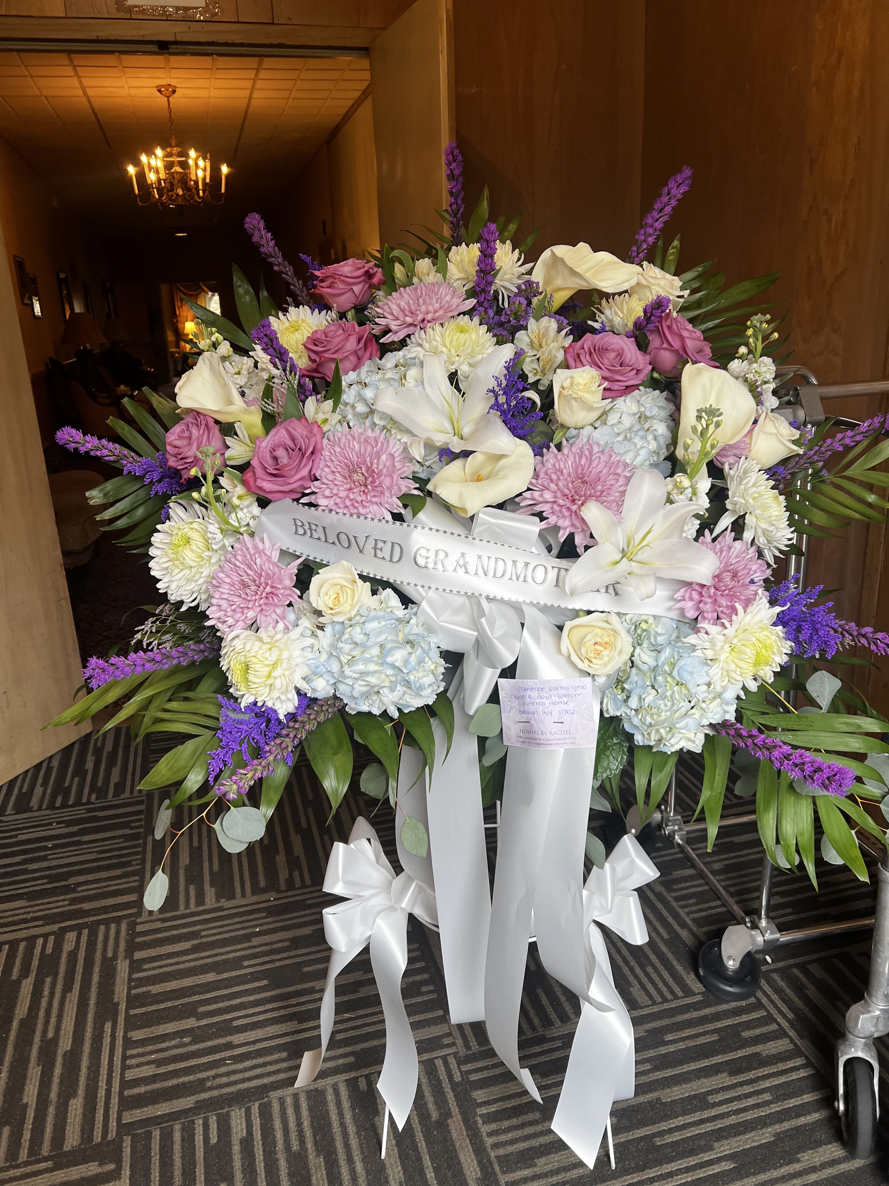 Large sympathy spray with pink, white, and purple flowers on a stand