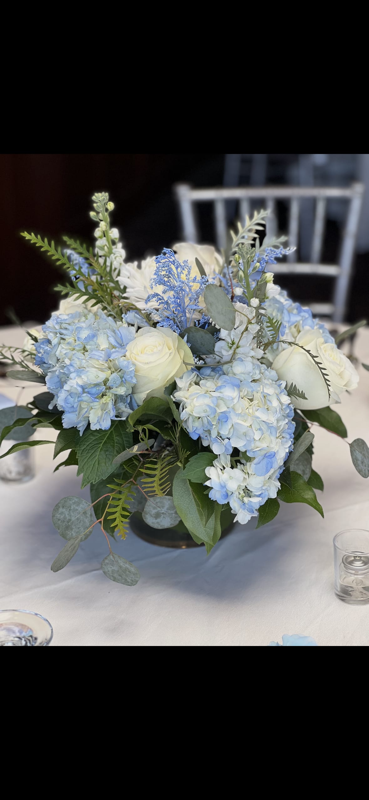 Blue hydrangeas and white roses arranged in a low centerpiece vase
