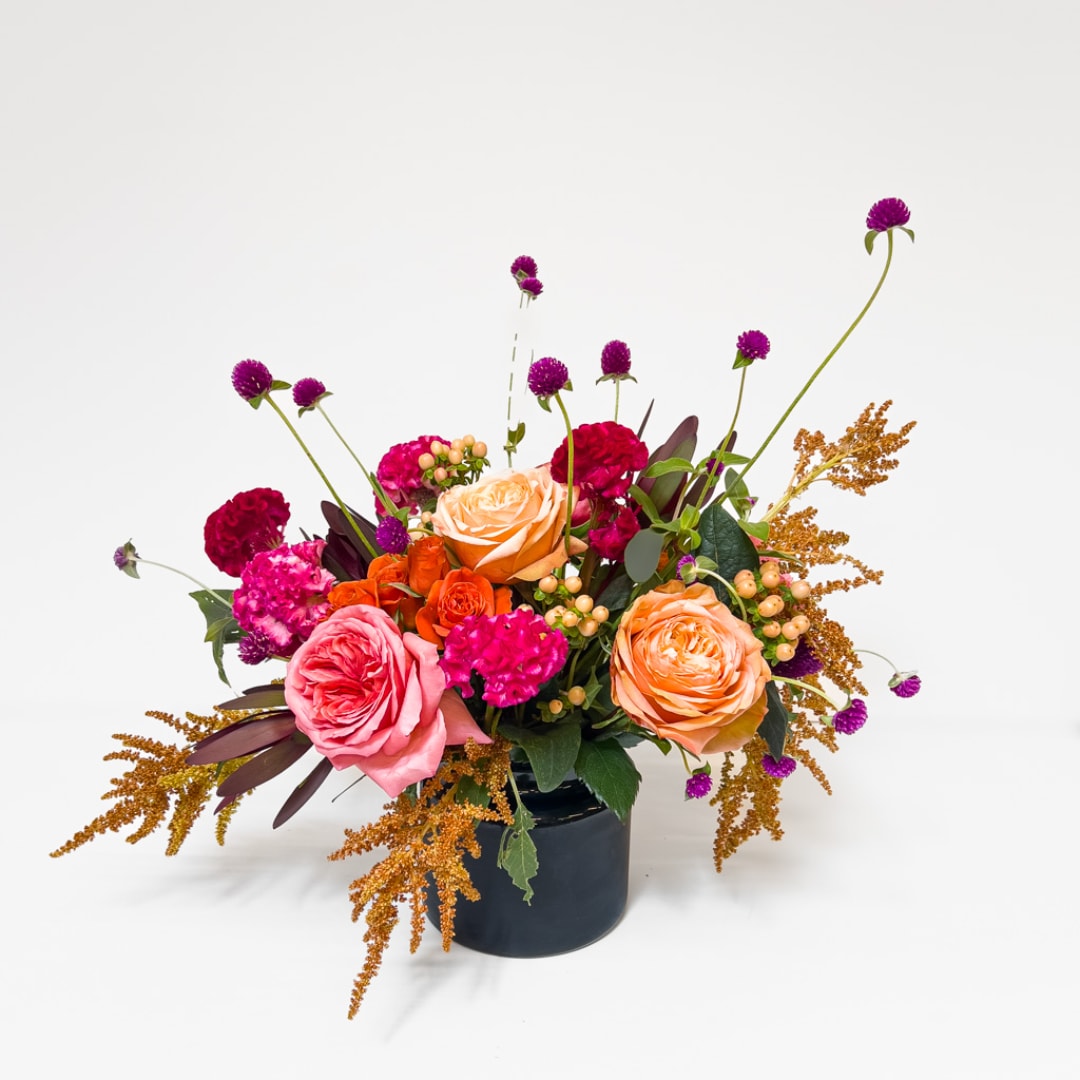 Mixed bouquet of roses and carnations in a dark vase