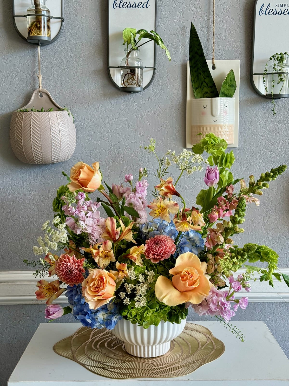 Mixed bouquet in a white ribbed vase with peach, pink, blue, and lavender flowers