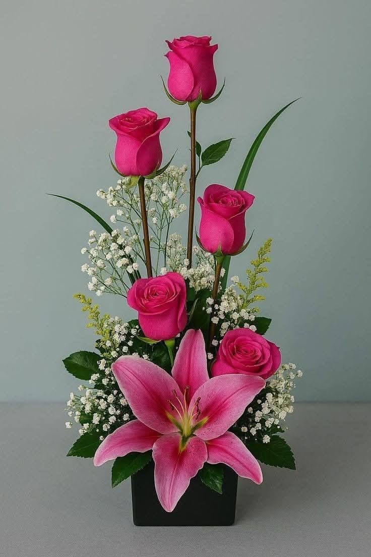Blushing Elegance - A graceful, vertical design that captures beauty in its purest form. Rich fuchsia roses rise with poise, creating height and sophistication, while a fully bloomed stargazer lily anchors the arrangement with a bold, captivating presence. Soft sprays of baby’s breath and delicate greenery add texture and airiness, allowing each bloom to shine. Blushing Elegance is perfect for expressing admiration, gratitude, or quiet luxury—an arrangement that feels both refined and effortlessly stunning. 