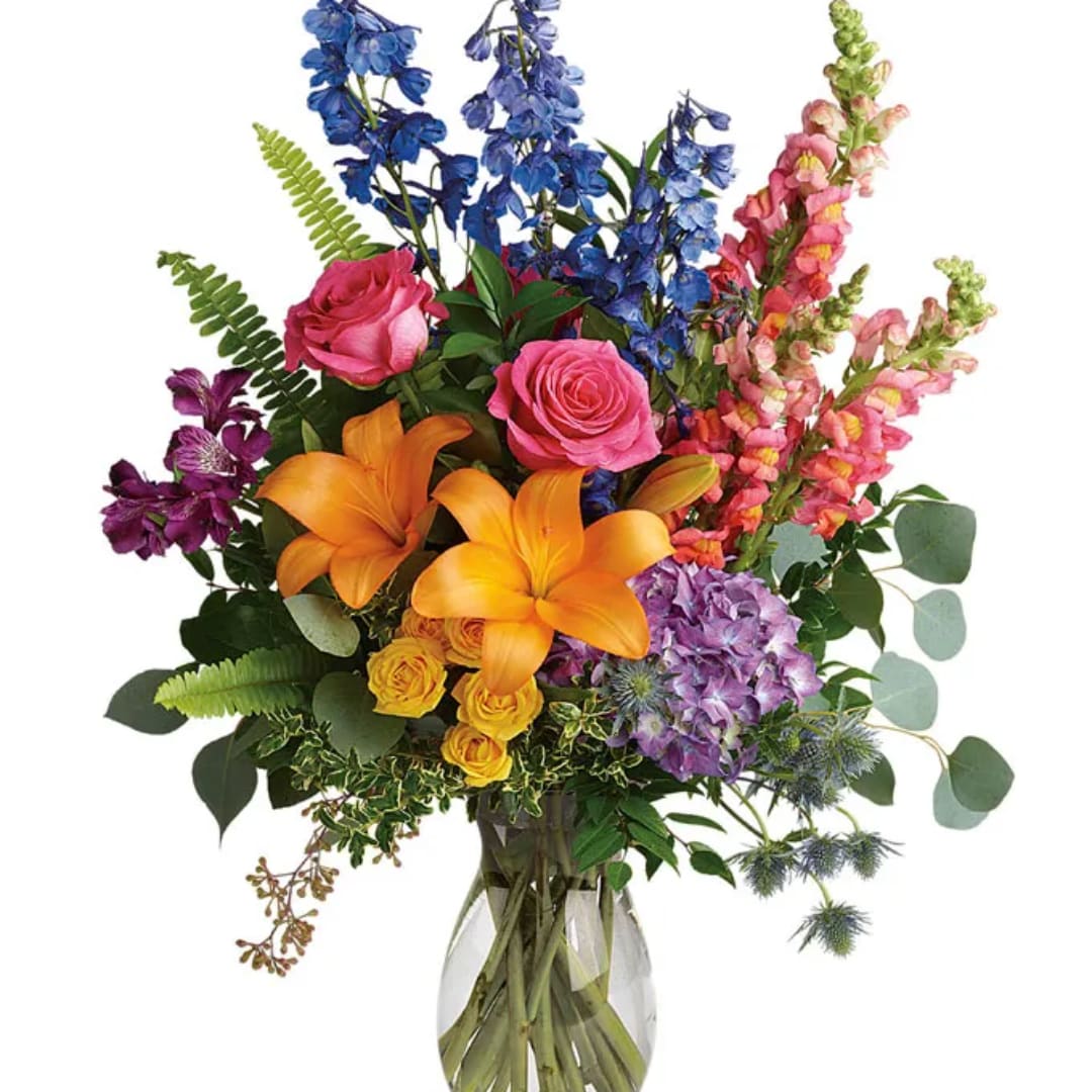 Mixed bouquet with roses, lilies, delphinium, and snapdragons in a glass vase