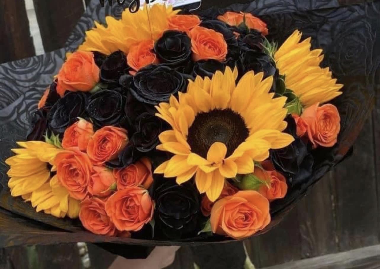 Hallovember - These colors can only please a certain type of girl. That girl that loves pumpkin spice,fall and all things awesome and spooky! Or maybe you just need something to spice up the office or lobby! This arrangement consists of black and orange roses, and sunflowers. It definitely takes a certain love for Fall and the colors that go with it.  **Pictured arrangement is of premium option. Please note standard and deluxe option will include less blooms but cost less. We’d like to give our customers some smaller, more affordable options. 