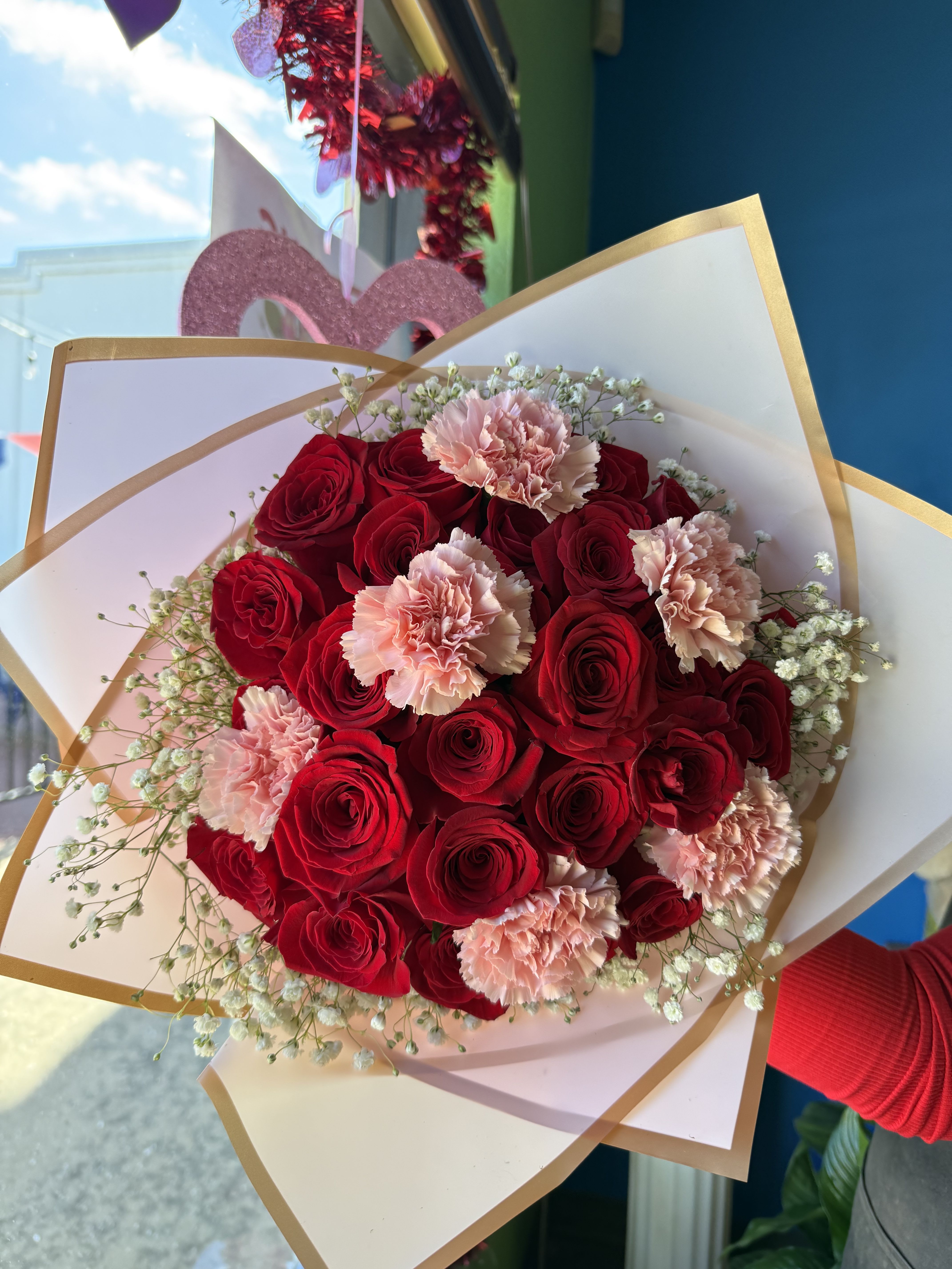 Bouquet of red roses and pale pink carnations wrapped in white paper