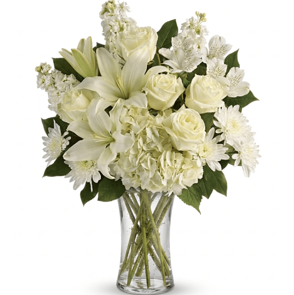 All-white bouquet of lilies, roses, hydrangeas, and other blooms arranged in a clear glass vase
