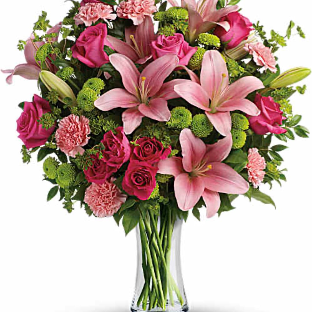 Pink lilies, roses, and carnations arranged in a clear glass vase