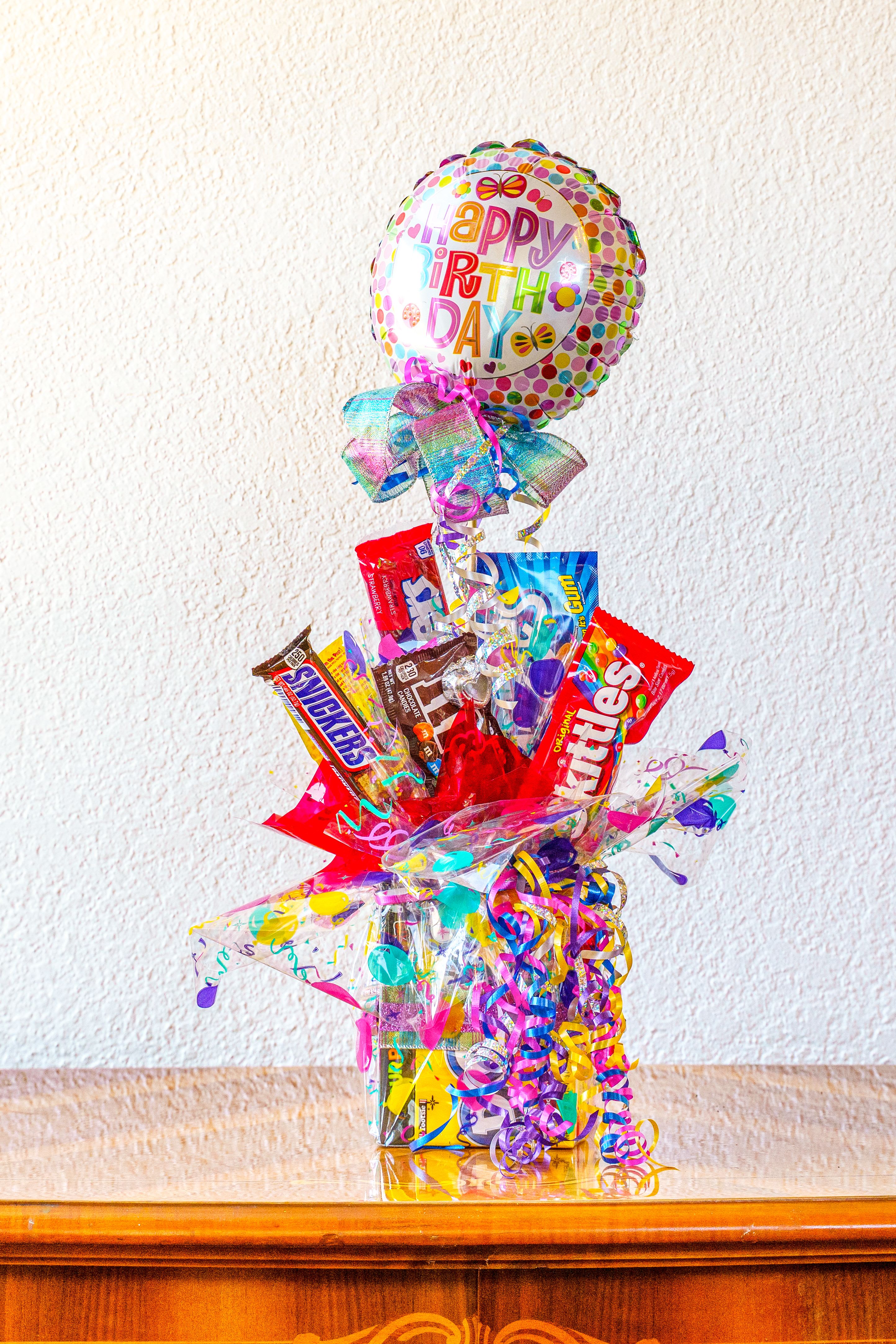 Birthday balloon and candy gift arrangement with colorful ribbons