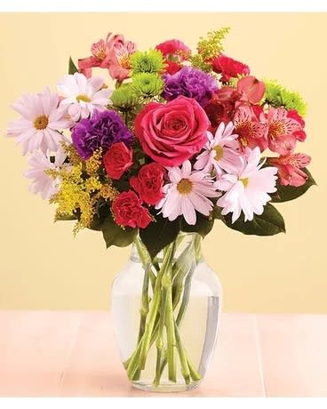 Mixed bouquet of pink roses, daisies, and carnations in a glass vase