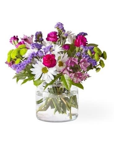 Mixed bouquet of daisies, carnations, and purple filler flowers in a glass vase
