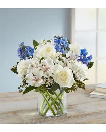 White and blue mixed bouquet in a clear glass vase
