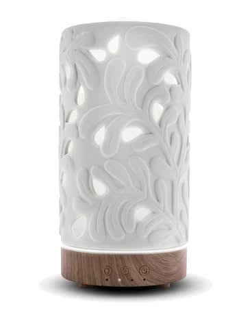 White carved diffuser with glowing cutout pattern and wood-look base