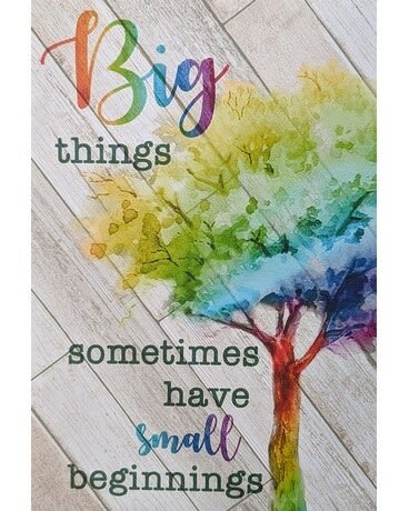 Decorative sign with rainbow tree and the words 'Big things sometimes have small beginnings' on a wood plank background
