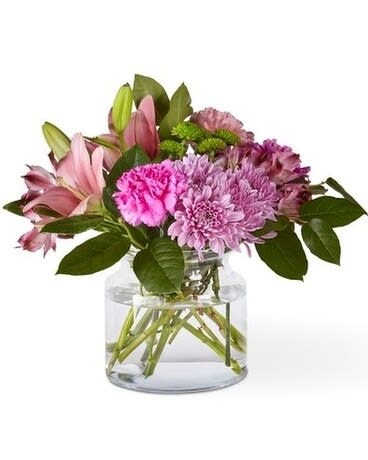 Pink lilies and purple flowers in a clear glass vase