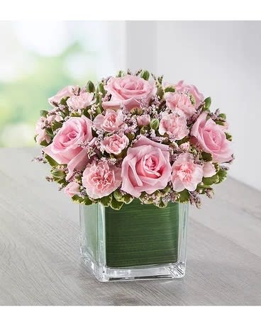 Pink roses and carnations arranged in a square glass vase