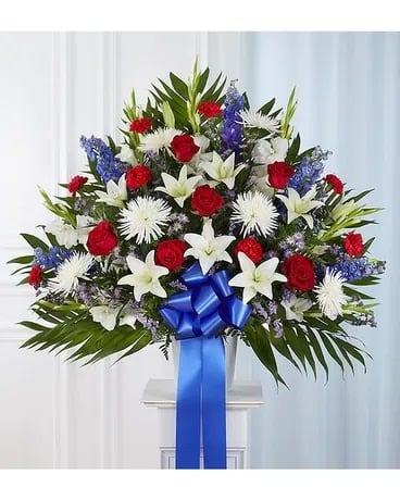 Standing floral spray with red and white flowers and a blue ribbon