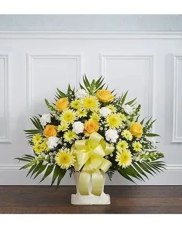 Yellow and white floral arrangement in a white vase with a ribbon