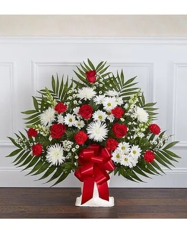 Standing floral spray with red roses and white daisies on a white easel