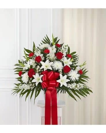 Standing floral spray with red roses, white lilies, and a red ribbon