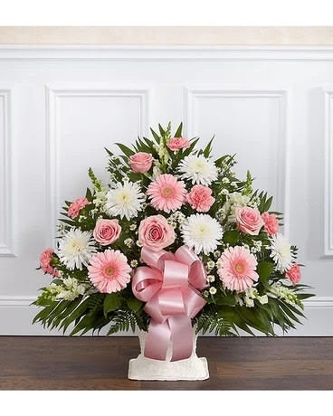 Pink and white floral arrangement with a pink ribbon bow in a white container