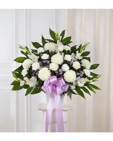 White funeral spray with a lavender ribbon on a stand
