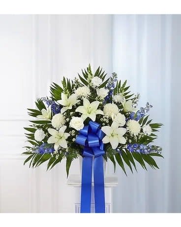 White floral standing spray with a blue ribbon on a pedestal