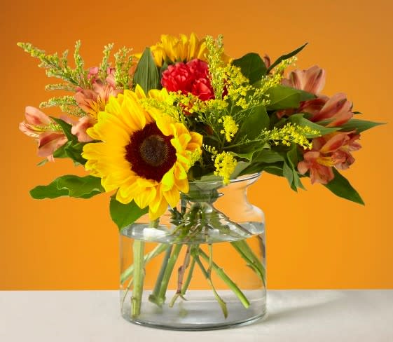 Sunflower and mixed flower bouquet in a clear glass vase
