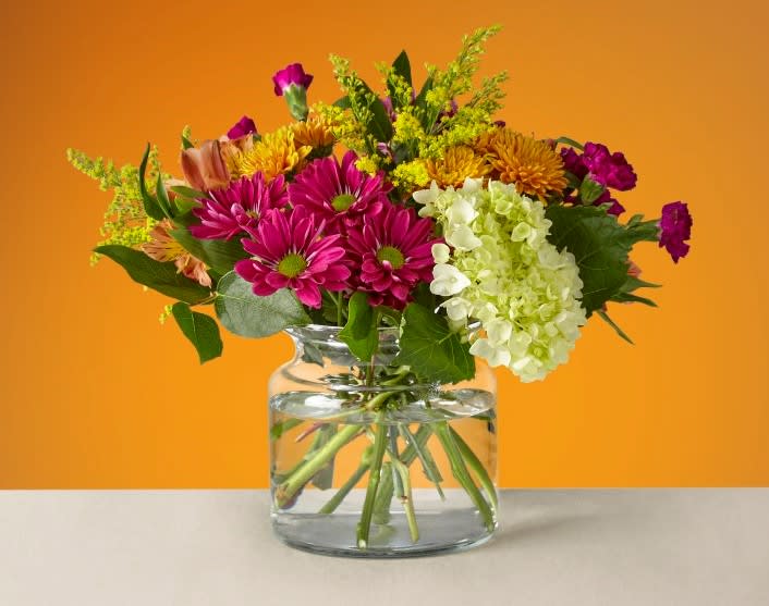 Mixed bouquet of pink and yellow flowers in a clear glass vase