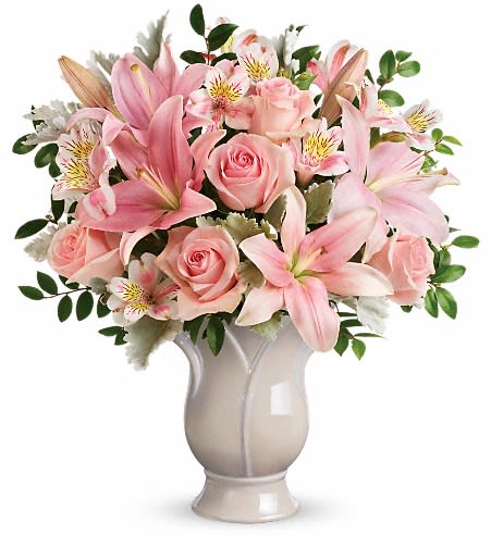 Pink lilies and roses arranged in a white vase