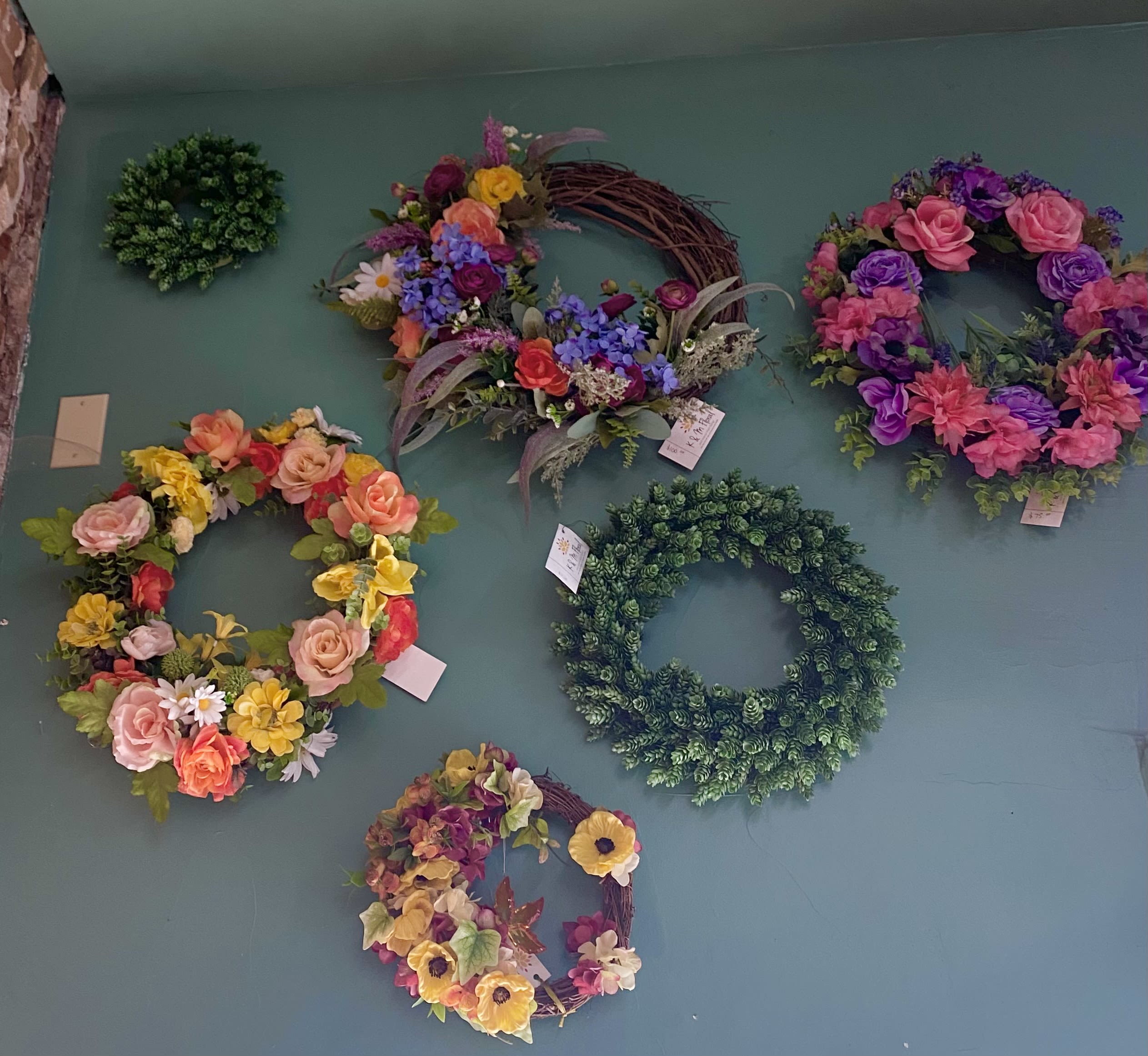 Wall display of colorful floral wreaths and greenery rings