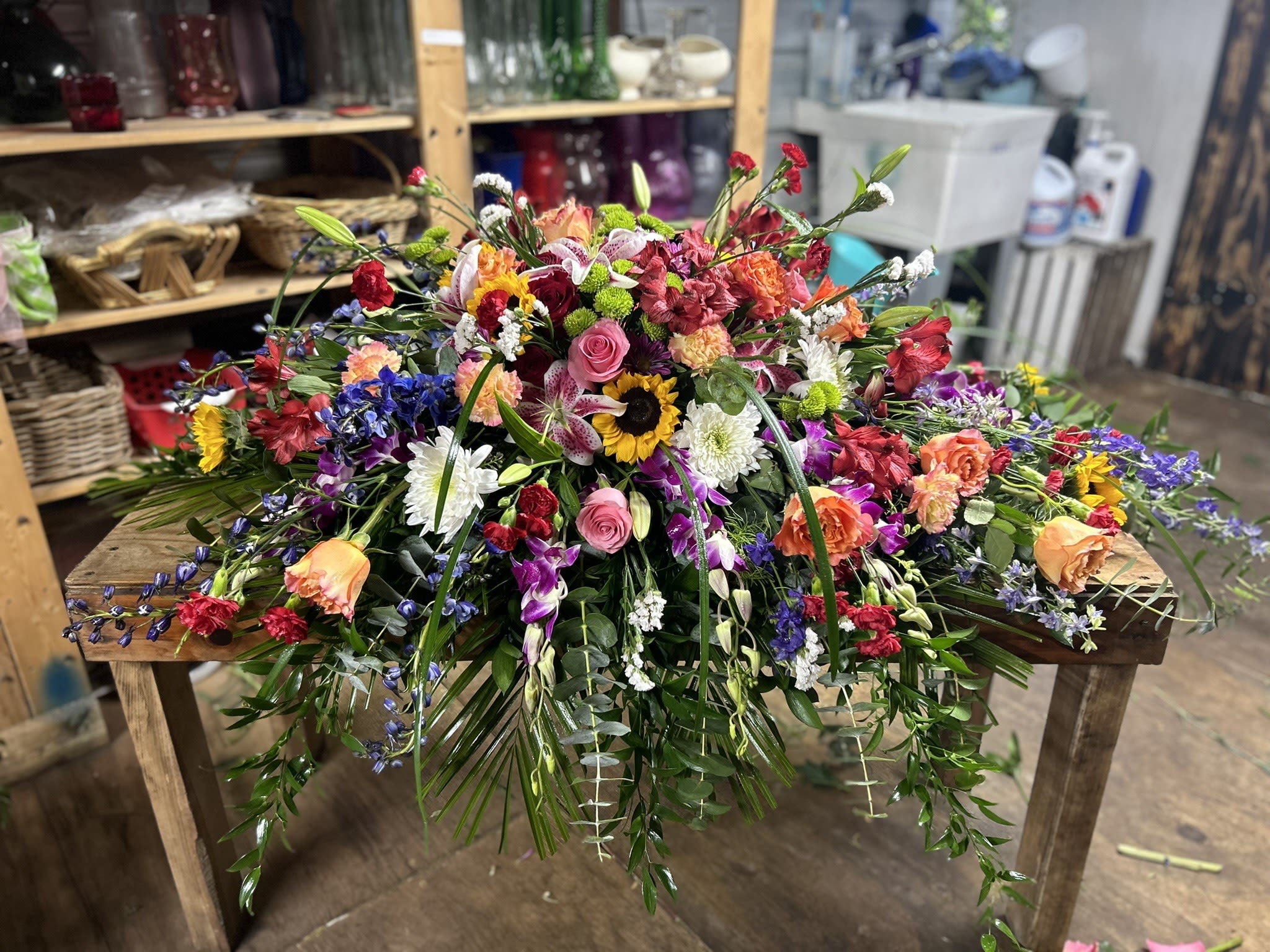 Large multicolored spray of mixed flowers cascading across a wooden table.
