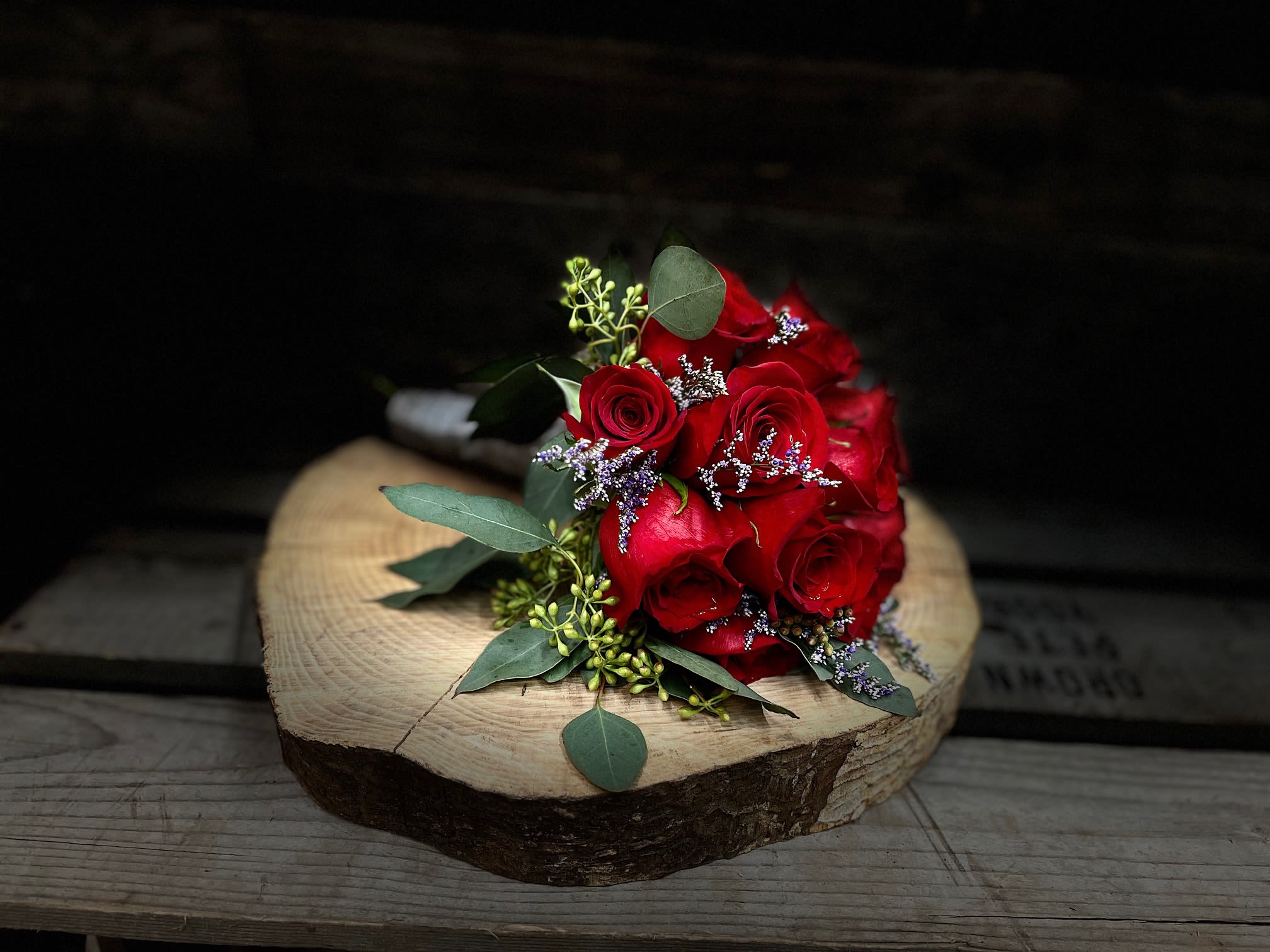 Red rose bouquet with eucalyptus on a wood slice