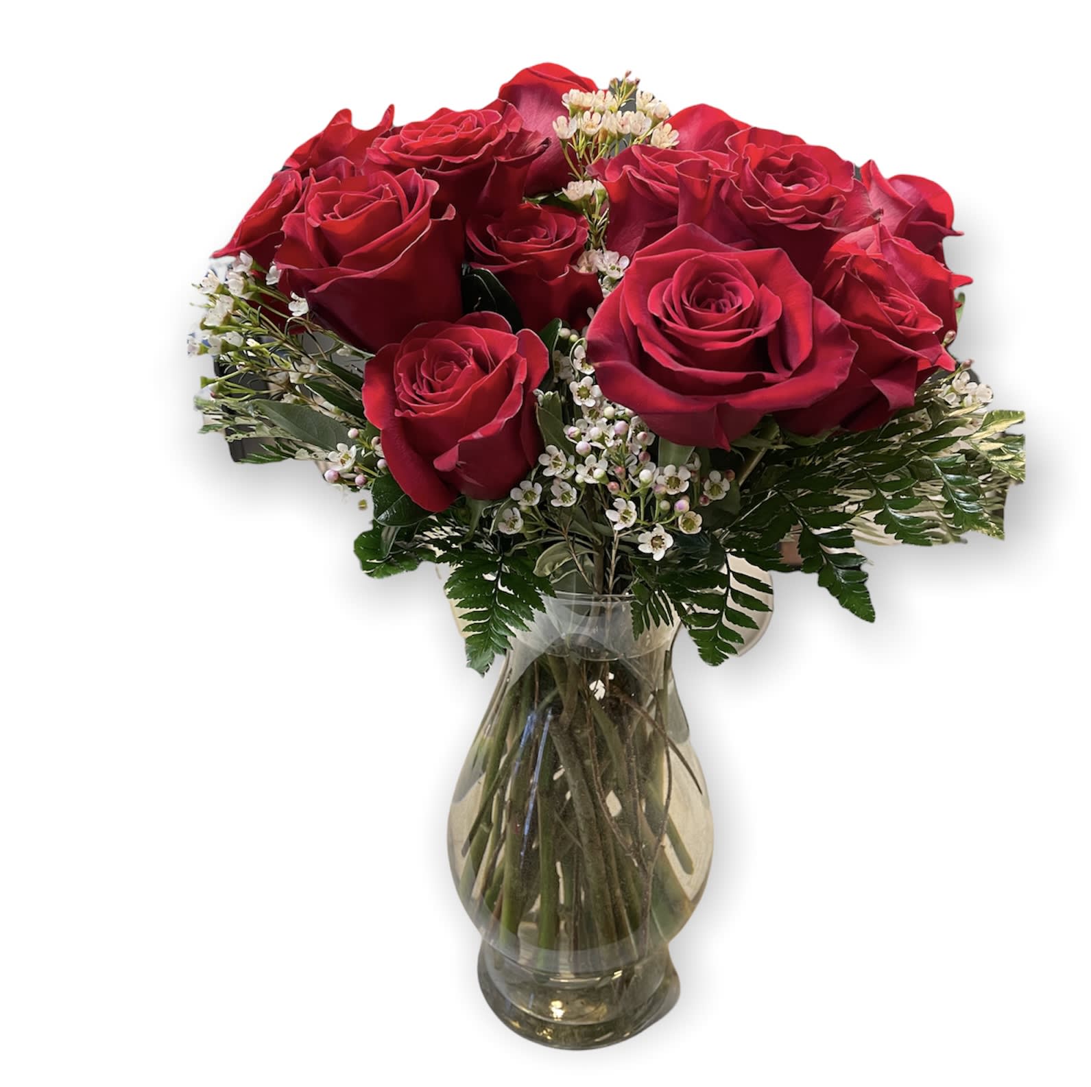 Red roses arranged in a clear glass vase with small white filler flowers