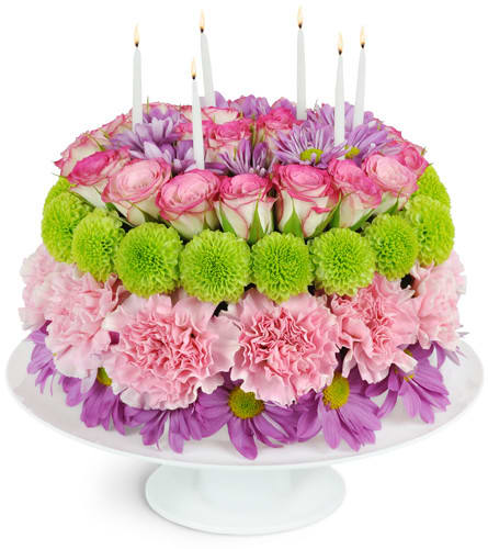 Round floral cake with pink and purple flowers and white candles
