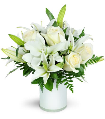 White lilies and roses arranged in a glass vase