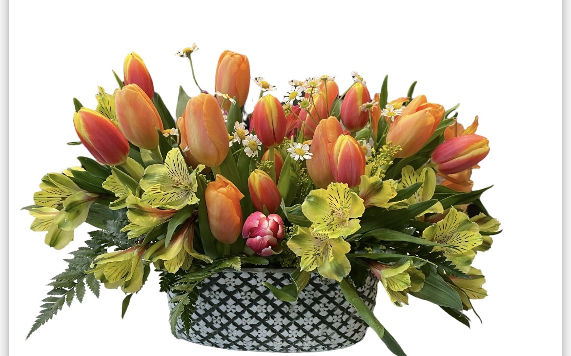 Basket of orange tulips and yellow flowers with greenery