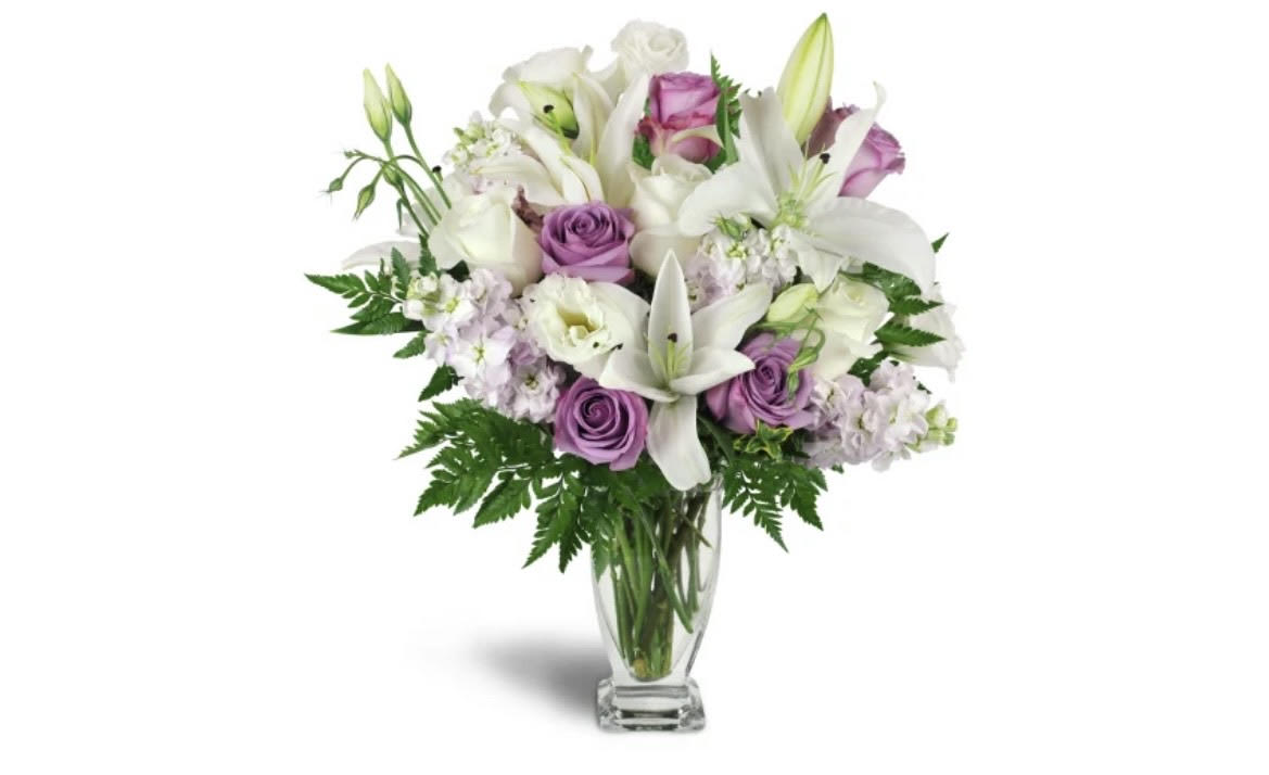 Bouquet of white lilies and lavender roses in a clear glass vase
