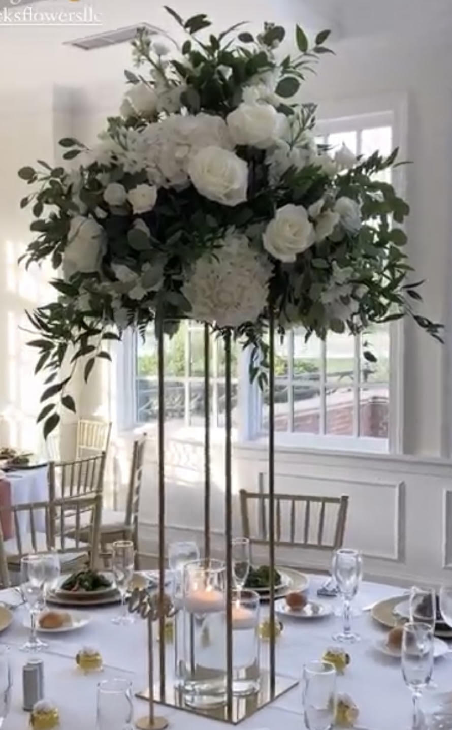 Tall white floral centerpiece on a gold stand above a banquet table