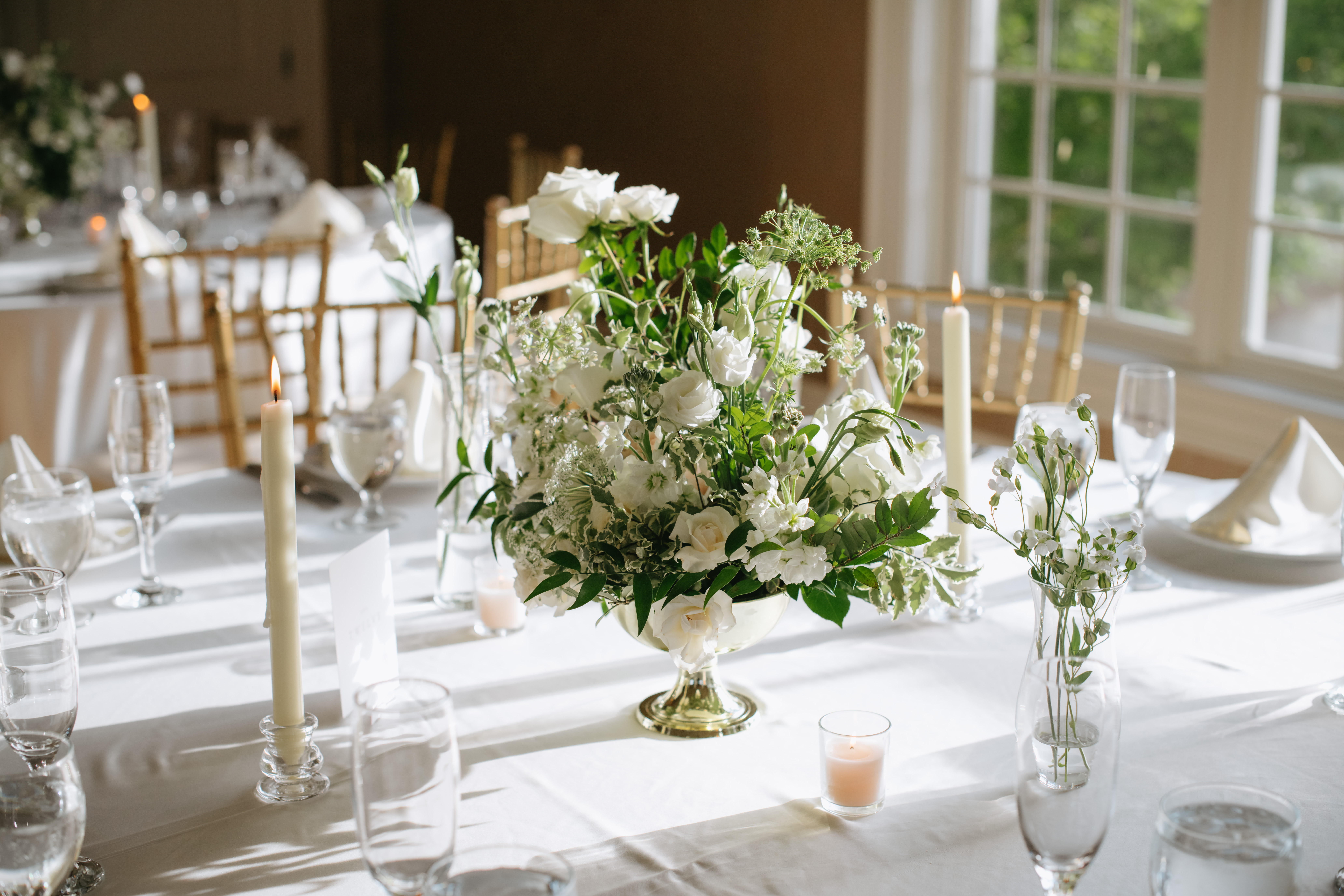 White floral centerpiece on a banquet table with candles