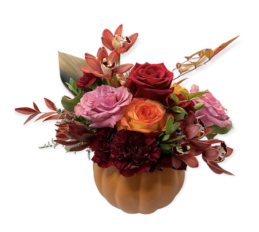 Bouquet of red, pink, and orange flowers in a pumpkin-shaped container